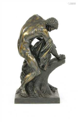 A large bronze figure of an athlete splitting a tree trunk,