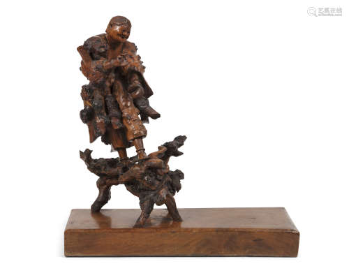 A JAPANESE CARVED BURL WOOD GROUP, c.1900, depicting a man standing on root wood and supported on