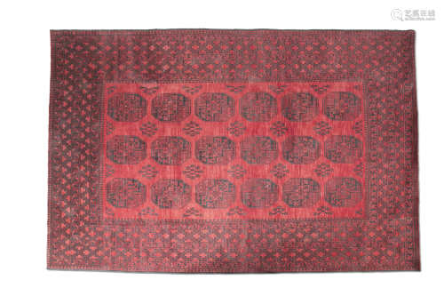 AN AFGHAN RED GROUND WOOL RUG, 20th century, of rectangular form, woven with three rows of octagons,