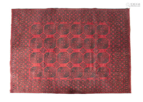 AN AFGHAN RED GROUND WOOL RUG, 20th century, of rectangular form, woven with four rows of