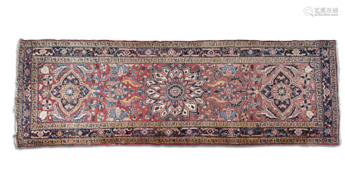 A PERSIAN RED GROUND WOOL RUNNER, of oblong form, woven with a large floral medallion and twin