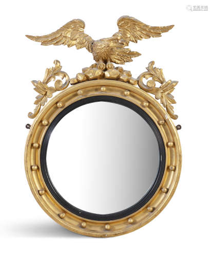 A CARVED GILTWOOD CONVEX MIRROR, 19th century, of circular form surmounted by an eagle, perched on