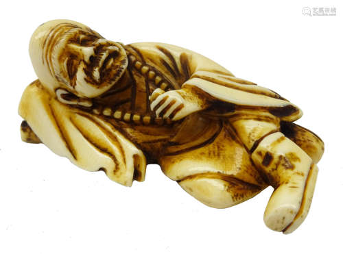 Japanese Meiji ivory Okimono modelled as a man laid, resting his head on a pillow,