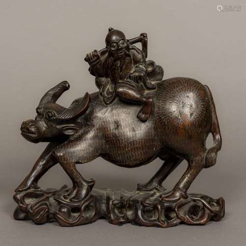 A Japanese white metal inlaid carved hardwood figure of a farmer riding a water buffalo On an