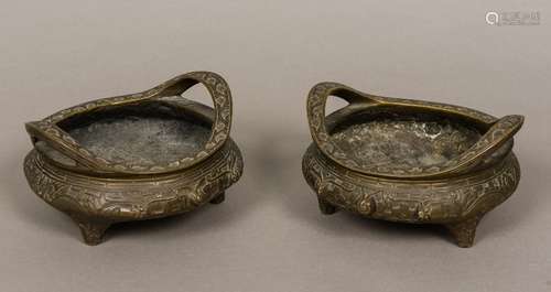 A pair of Chinese cast bronze censers Each of squat circular form with twin handles,