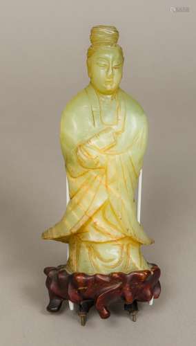 A Chinese carved jade figurine modelled as Guanyin Mounted on a carved wooden base. 27.5 cm high.