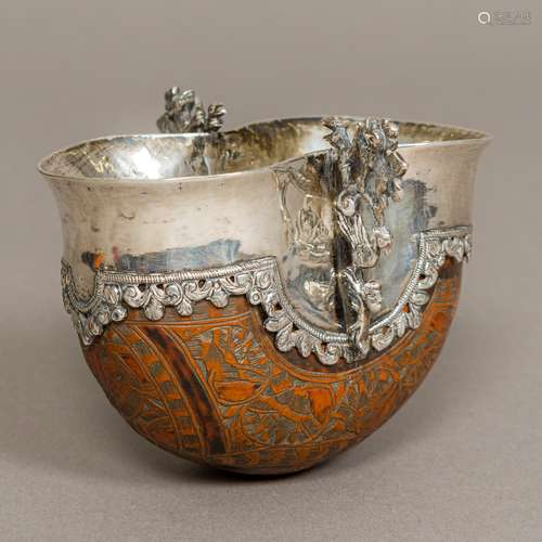 An 19th century white metal (probably silver) mounted carved coquilla nut twin handled tasting