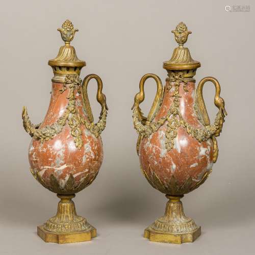 A pair of gilt metal mounted red marble baluster garniture vases and covers With floral swags and