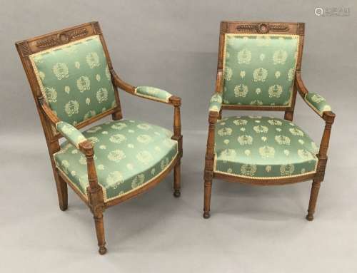 A pair of French Empire period walnut and beech framed upholstered open armchairs Each with laurel