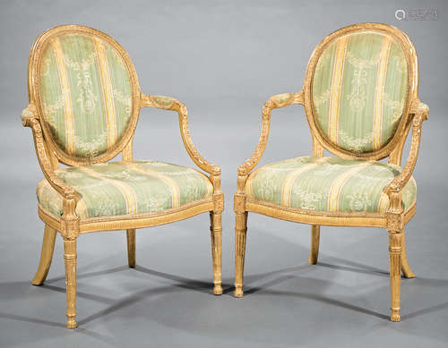 Pair Louis XVI-Style Giltwood Fauteuils , oval back, padded arms, floral-blocked seat rail, fluted