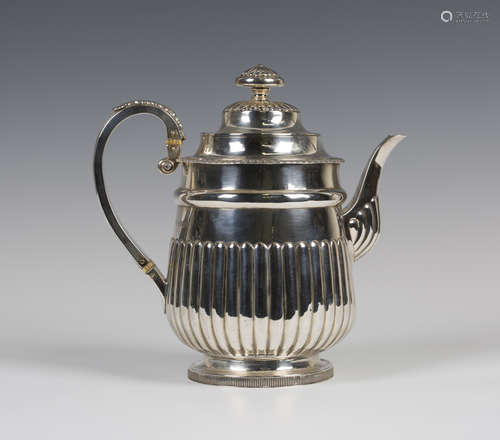 A George III silver coffee pot of half-reeded form with foliate capped scroll handle, on a