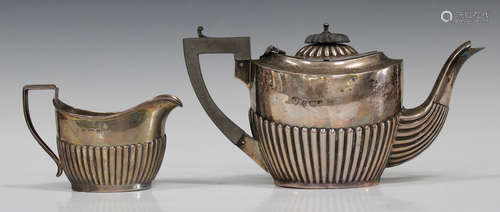 An Edwardian silver bachelor's teapot with half-reeded decoration and a matching milk jug,