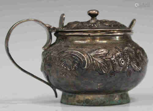 A George III silver circular mustard, the squat body and hinged lid decorated in relief with flowers