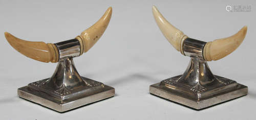 A pair of Edwardian silver and ivory mounted knife rests, designed as a pair of carved ivory '