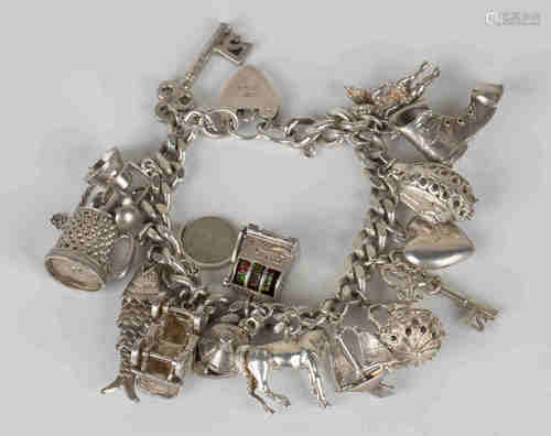 A silver faceted curblink charm bracelet, fitted with a variety of mostly silver charms, including a