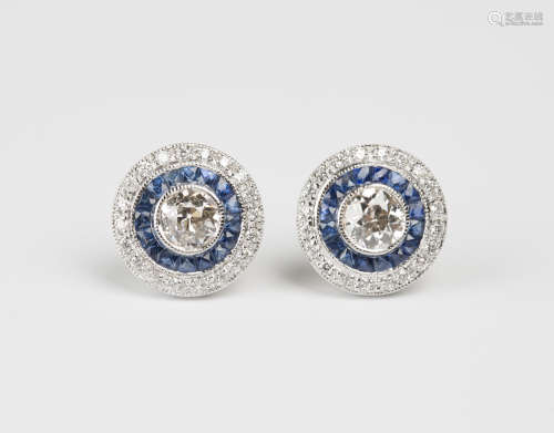 A pair of 18ct white gold, diamond and sapphire earrings, each collet set with a principal