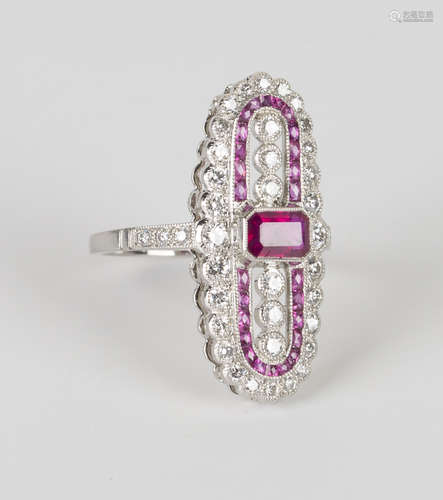 A platinum, ruby and diamond oval panel shaped ring, collet set with an emerald cut ruby between two