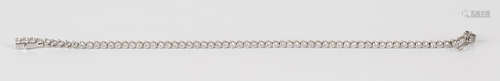 A white gold and diamond line bracelet, claw set with a row of circular cut diamonds, on a snap