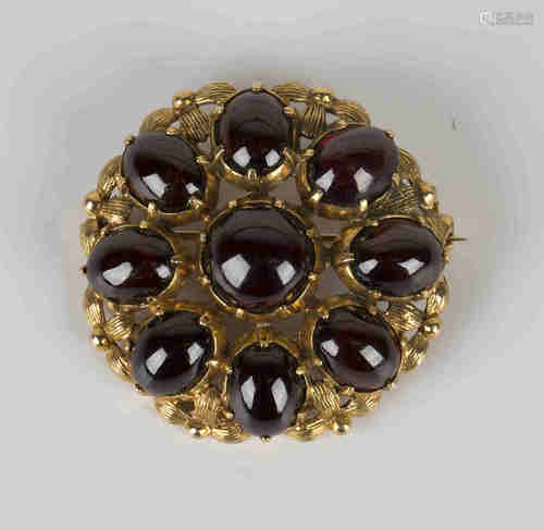 A 9ct gold and carbuncle garnet brooch of shaped circular form, mounted with a circular carbuncle