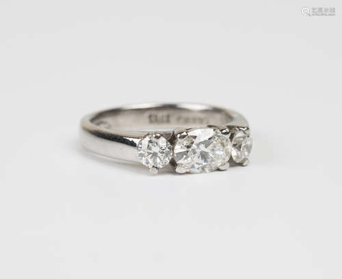 A white gold and diamond three stone ring, claw set with the principal oval cut diamond between