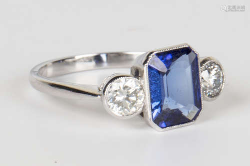 A white gold, tanzanite and diamond ring, mounted with an emerald cut tanzanite between circular cut