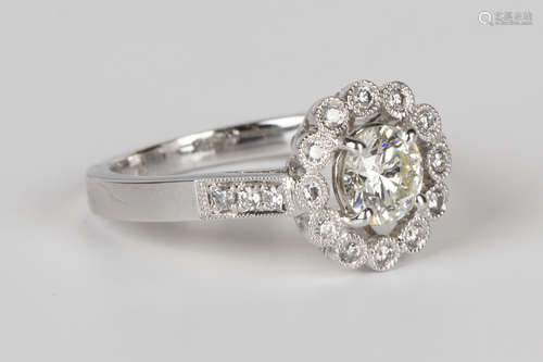 A white gold and diamond ring, claw set with the principal circular cut diamond within an open