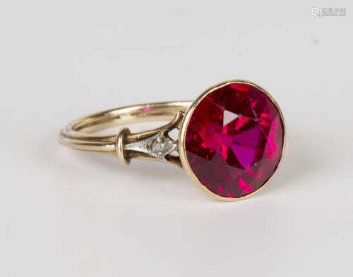 A gold ring, collet set with a circular cut synthetic ruby between rose cut diamond set shoulders,