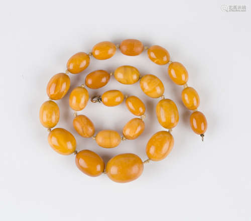 A single row necklace of twenty-three graduated oval vari-coloured opaque butterscotch coloured