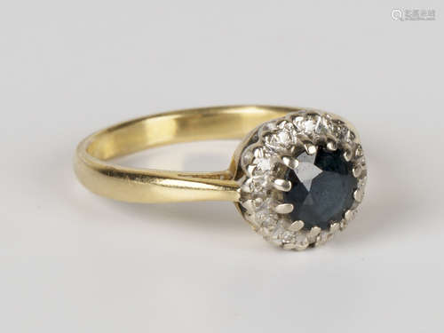 A gold, sapphire and diamond circular cluster ring, claw set with a circular cut sapphire within a