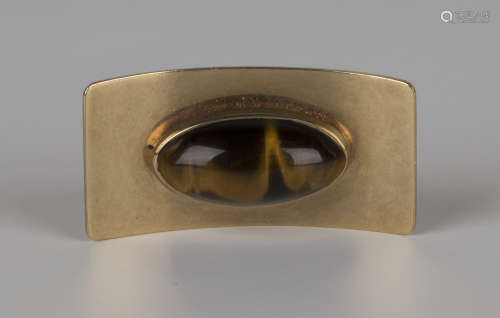 A South African gold and tiger's eye brooch in a curved rectangular design, mounted with an oval