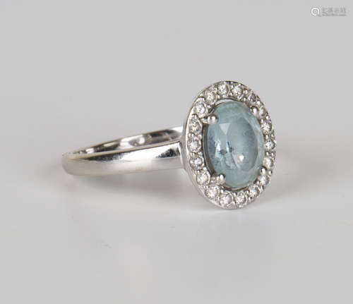 An 18ct gold, aquamarine and diamond oval cluster ring, claw set with the oval cut aquamarine within