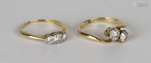 A gold and diamond two stone ring, claw set with cushion shaped diamonds in a cross-over design,