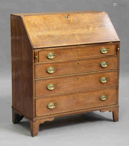 A George III oak bureau, crossbanded in mahogany, the fall flap revealing a fitted interior above