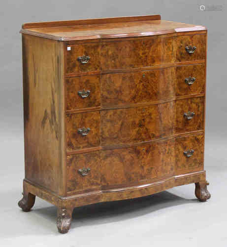 A George V burr walnut serpentine fronted chest of four graduated long drawers, on scroll feet,