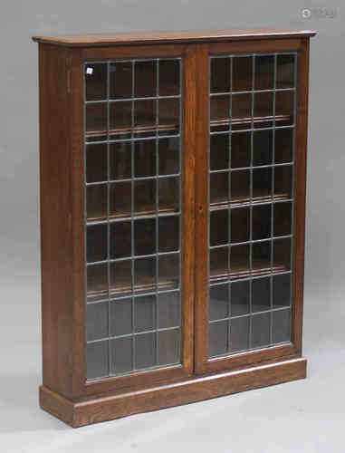 A George V oak bookcase, enclosed by two leaded glazed doors, on a plinth base, height 122cm,