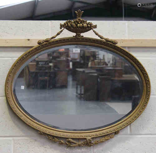 An early 20th century Neoclassical Revival oval gilt framed wall mirror with urn and swag