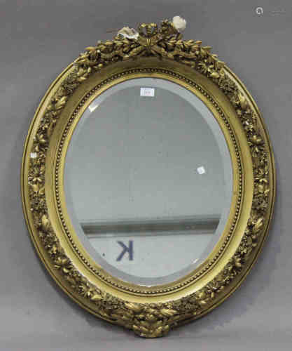 A late 19th century gilt composition oval wall mirror with ribbon and torch surmount, 87cm x 73cm (