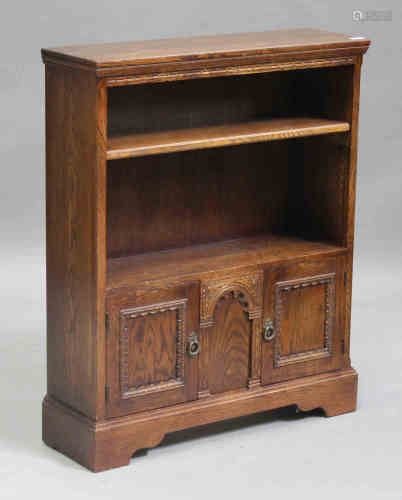 A 20th century oak open bookcase, fitted with an adjustable shelf above a pair of panel cupboard