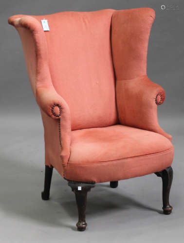 An early 20th century wing back armchair, upholstered in pink velour, on cabriole legs and pad feet,