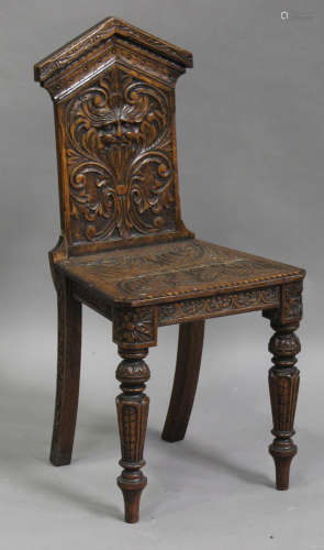 A late Victorian carved oak hall chair, the shaped back carved with a Green Man mask, the solid seat