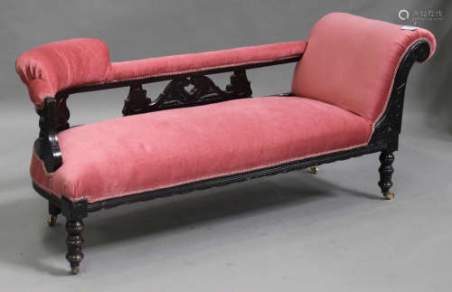An Edwardian stained beech framed chaise longue, upholstered in pink fabric, on turned legs,