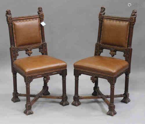 A pair of late 19th/early 20th century French Gothic walnut side chairs with carved head finials,