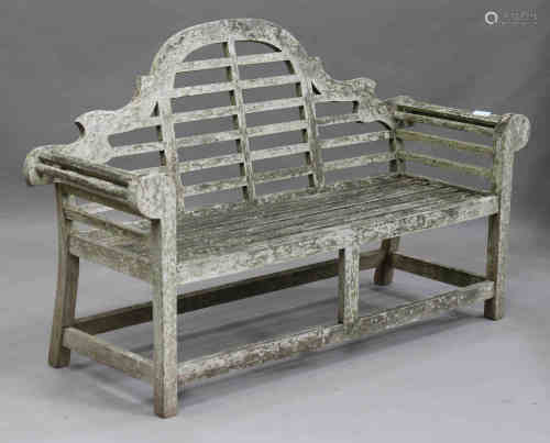 A late 20th century teak garden bench, after a design by Sir Edwin Lutyens, the arched and slatted