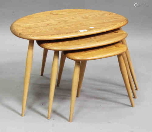 An Ercol elm and beech nest of three occasional tables, the shaped tops raised on turned legs,