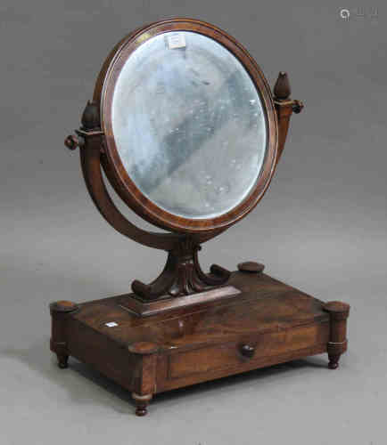 An early 19th century figured mahogany circular swing frame toilet mirror, the base fitted with a