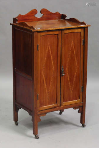 An Edwardian mahogany music cabinet, the shaped gallery back above a pair of inlaid panel doors,
