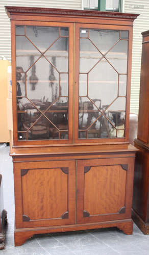 A late Victorian mahogany bookcase cabinet, the dentil moulded pediment above a pair of astragal