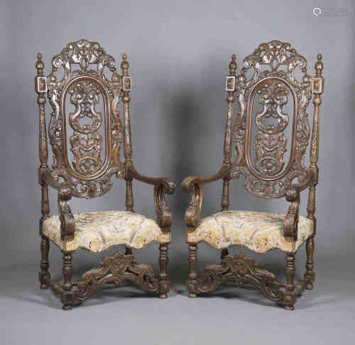 A pair of late 19th/early 20th century French carved walnut throne chairs, profusely carved with