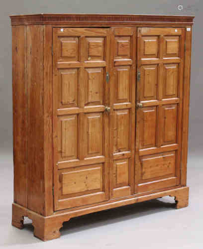 A George III pine side cabinet, the fluted frieze above a pair of panelled doors revealing a green