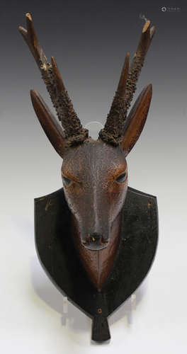 A 19th century Continental carved and stained wooden model of a deer's head, mounted on a wall